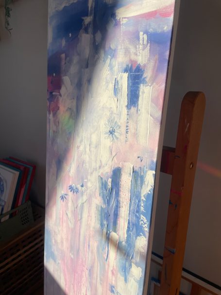 Abstrakte Malerei in Blau- und Rosatönen auf einer Leinwand, teilweise beleuchtet.